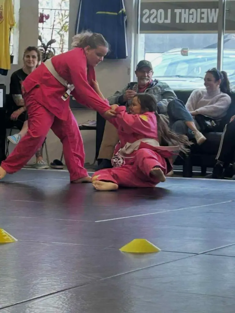 Adult martial arts student practicing a controlled partner drill while classmates observe during training, demonstrating martial arts etiquette for beginners.